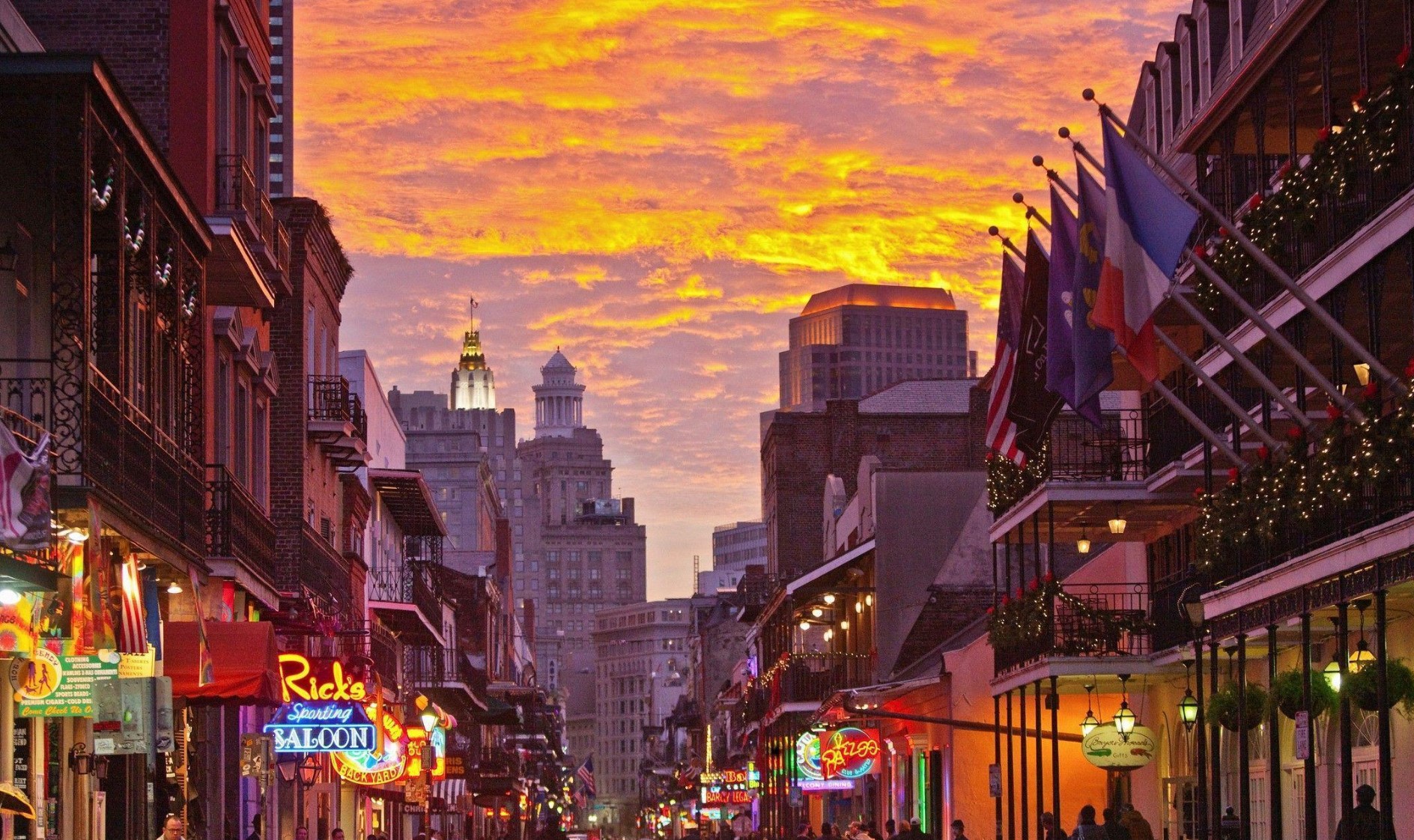 Sunset over Bourbon Street in New Orleans, with the sky ablaze in warm hues above the vibrant streets of the French Quarter