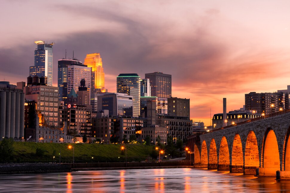 Downtown Minneapolis skyline, with its reflective glass skyscrapers against the backdrop of a dusky sky.