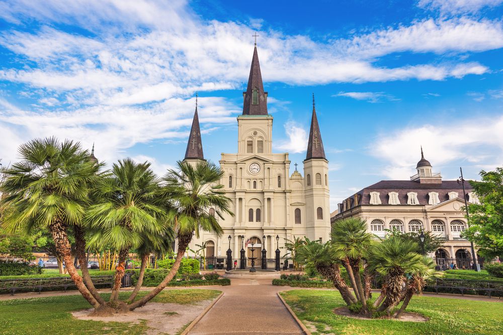 Iconic view of Jackson Square in New Orleans with the historic St. Louis Cathedral in the background and lively greenery in the foreground.
