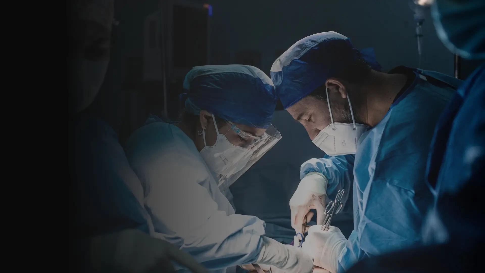 Two surgeons in full PPE collaborating in an operating room, symbolizing excellence in academic medicine, physician recruitment, and healthcare leadership.